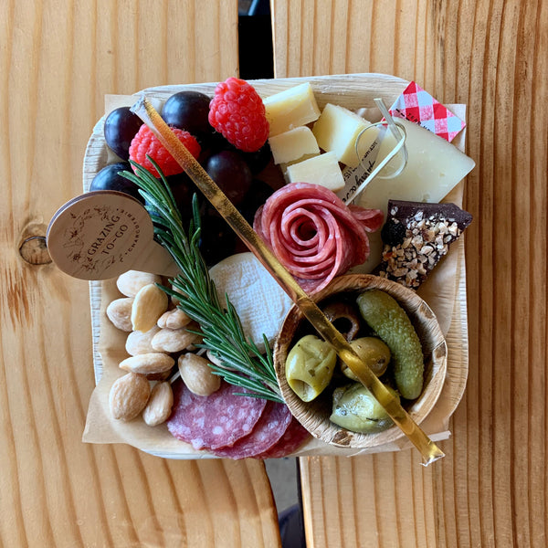 Charcuterie meats, cheeses, fruit, nuts, olives, pickles and accompaniments on a tray inside a Kraft box. Serves 1-2 as appetizer portions. The Mini Graze.