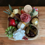 Charcuterie meats, cheeses, fruit, nuts, olives, pickles and accompaniments on a tray inside a Kraft box. Serves 1-2 as appetizer portions. The Mini Graze.