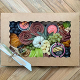 Charcuterie meats, cheeses, fruit, nuts, olives, pickles and accompaniments on a tray inside a Kraft box. Serves 6-8 as appetizer portions. The Gathering.